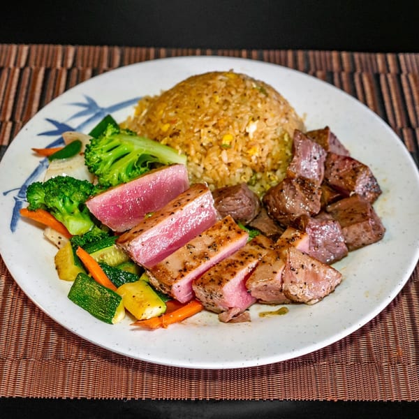 Hibachi meal with seared tuna, steak, fried rice, and mixed vegetables on a white plate.