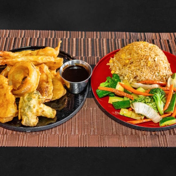 Hibachi meal with fried tempura vegetables, dipping sauce, fried rice, and steamed vegetables.